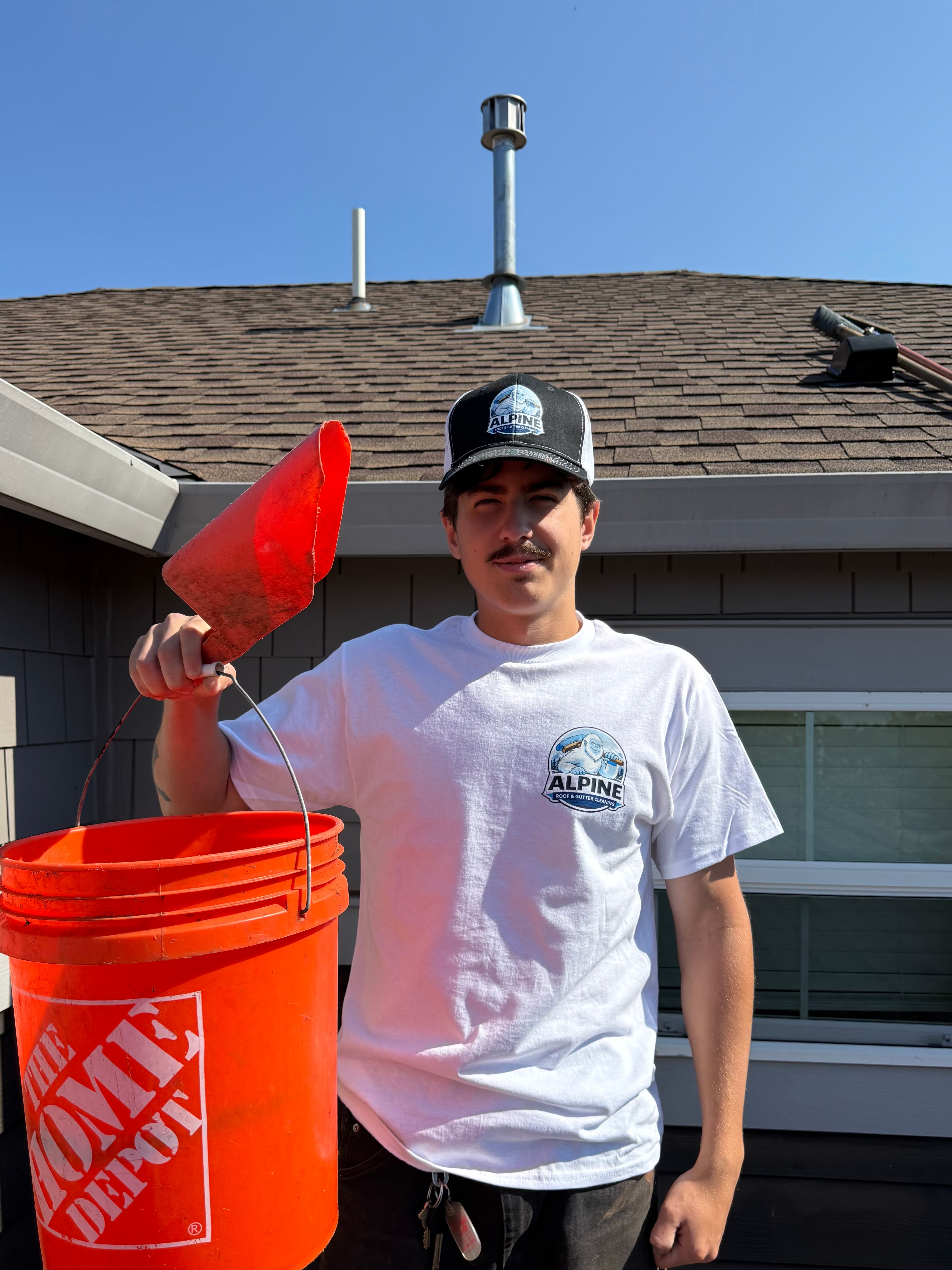 Dan from Alpine Roof and Gutter Cleaning holding a bucket and gutter scoop